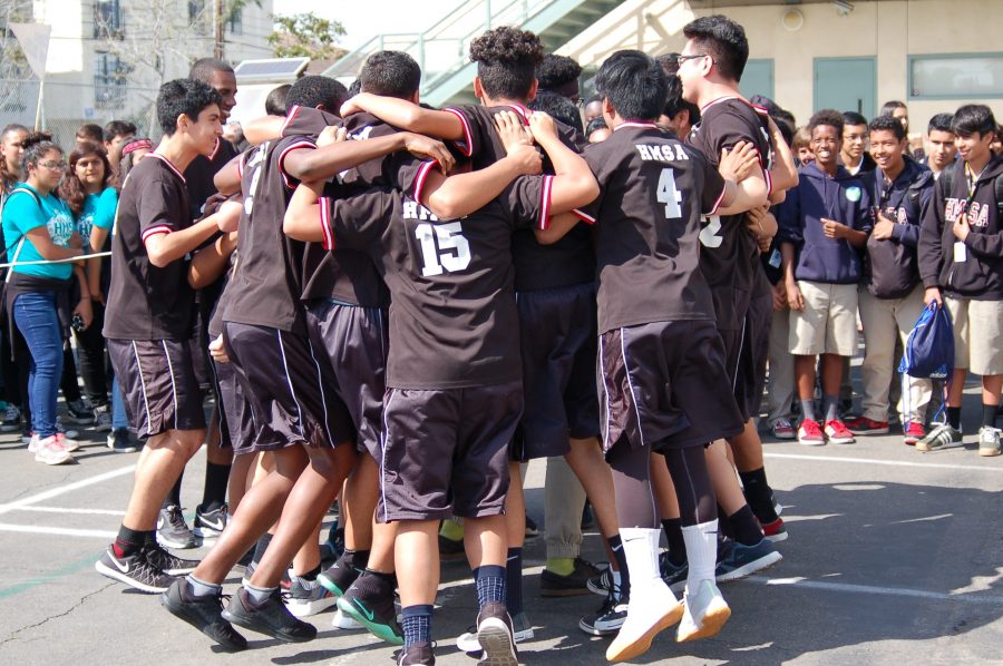 The boys volleyball team huddle together to say their chant. 