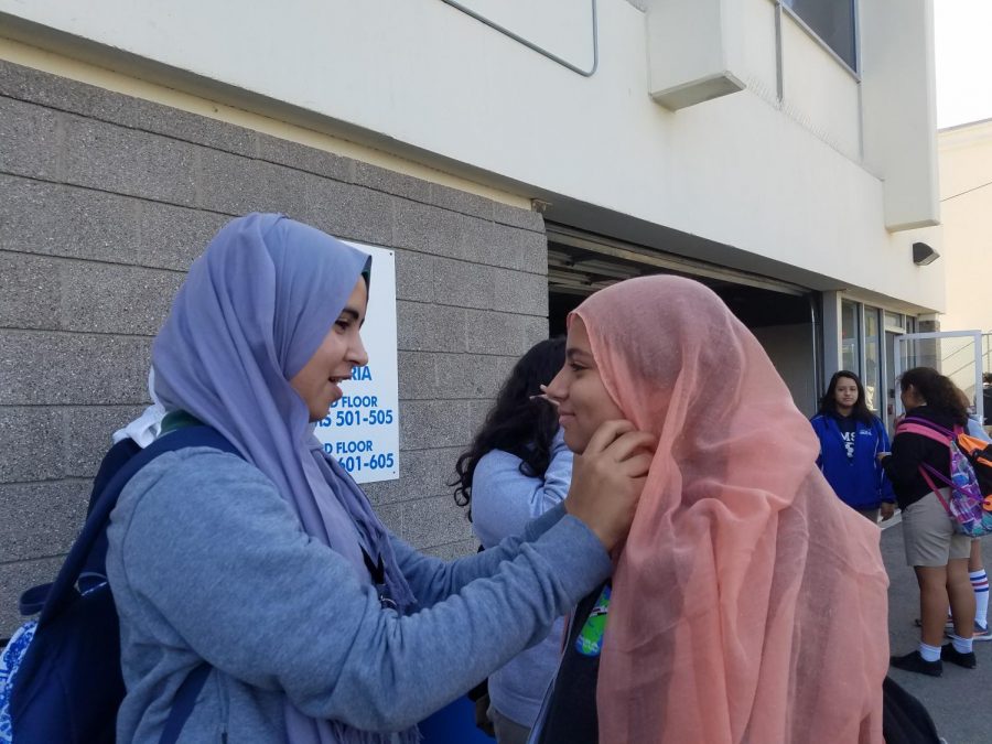 Students helping each other putting on the hijab. 